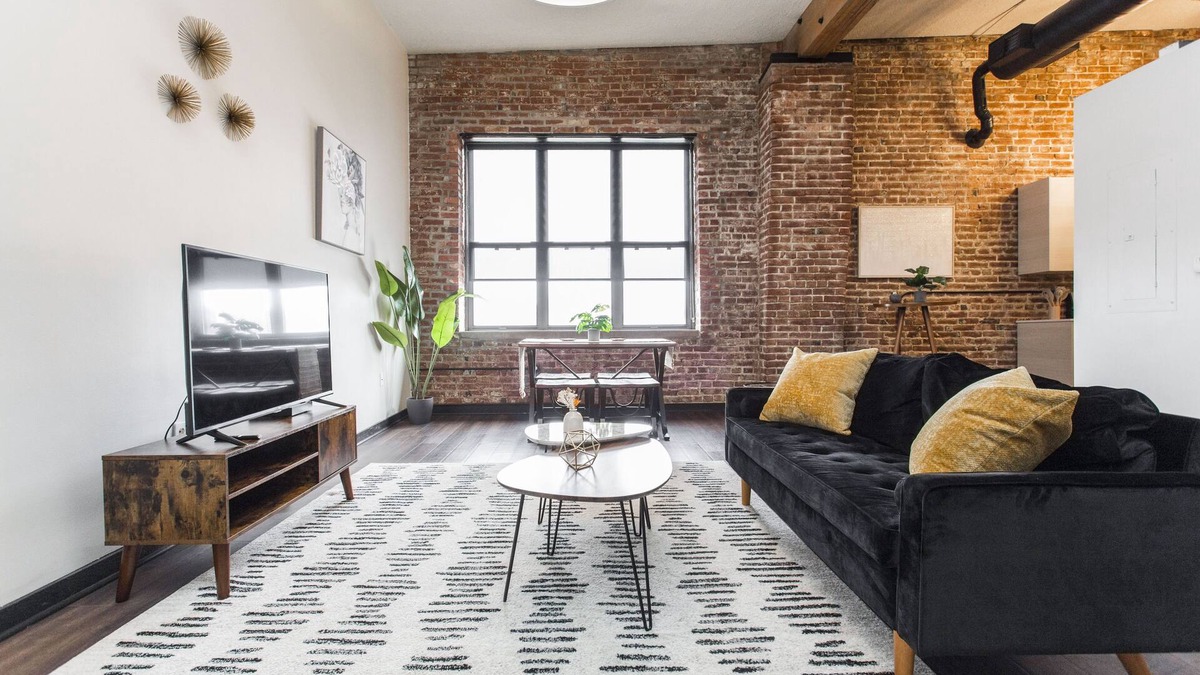 Kansas City Apartment | Exposed brick, wood beams, & chic touches give this loft serious style. Enjoy skyline views from the rooftop, a full kitchen with coffee bar, king bed, on-site gym, & quick access to the free KC streetcar. Walk to shops/dining, and the City Market!