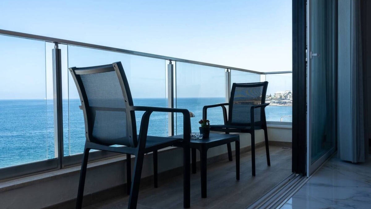 Bugibba Apartment | Seafront Bugibba apartment with balcony and stunning 180° views. Bright, beach-style interiors, lift access, and steps from dining and the shoreline.