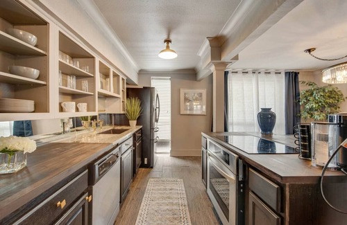 Lower Greenville Condo | Upscale 2BR Dallas condo with pool view and access to an award-winning courtyard featuring a resort-style pool, hot tub, dry sauna, and lush lounge areas. Enjoy a 77″ smart TV, sleek leather sofa, and modern kitchen for a stylish, comfortable stay.