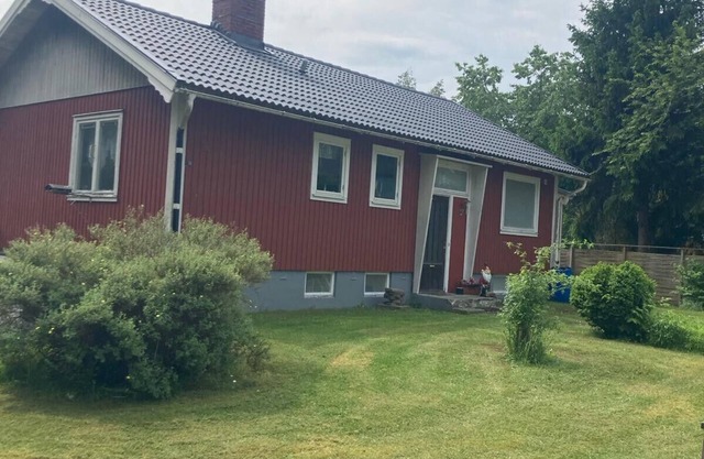 Red and white vacation home in Småland near a lake with boat